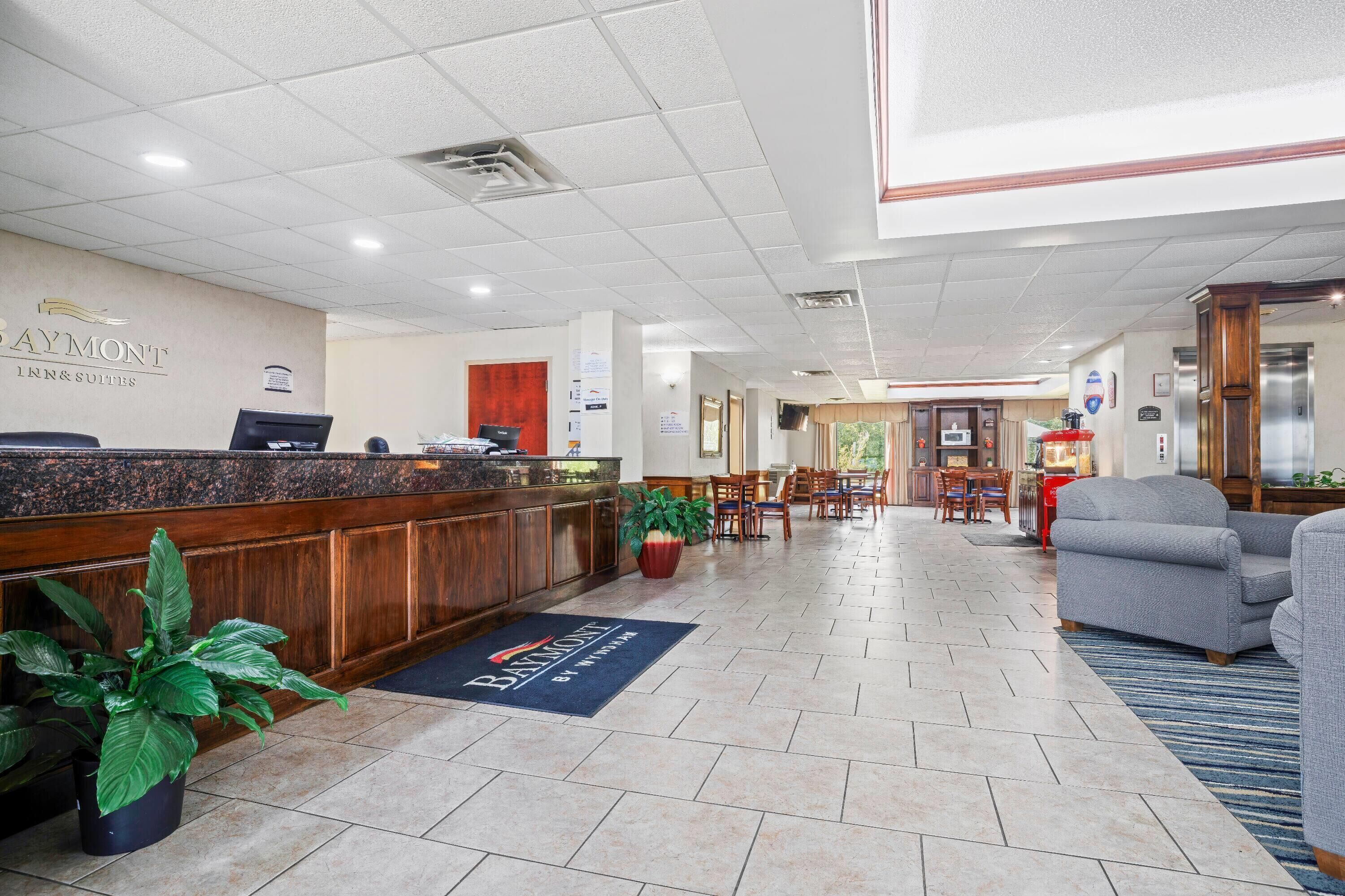 A hotel lobby with a reception desk, seating area, and a view of the dining room.