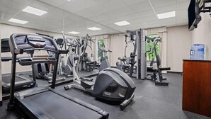 Un gimnasio con cintas de correr, elípticas y equipo de pesas.