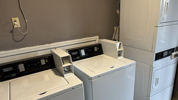 A laundry area with two front-loading washing machines and a stacked dryer.