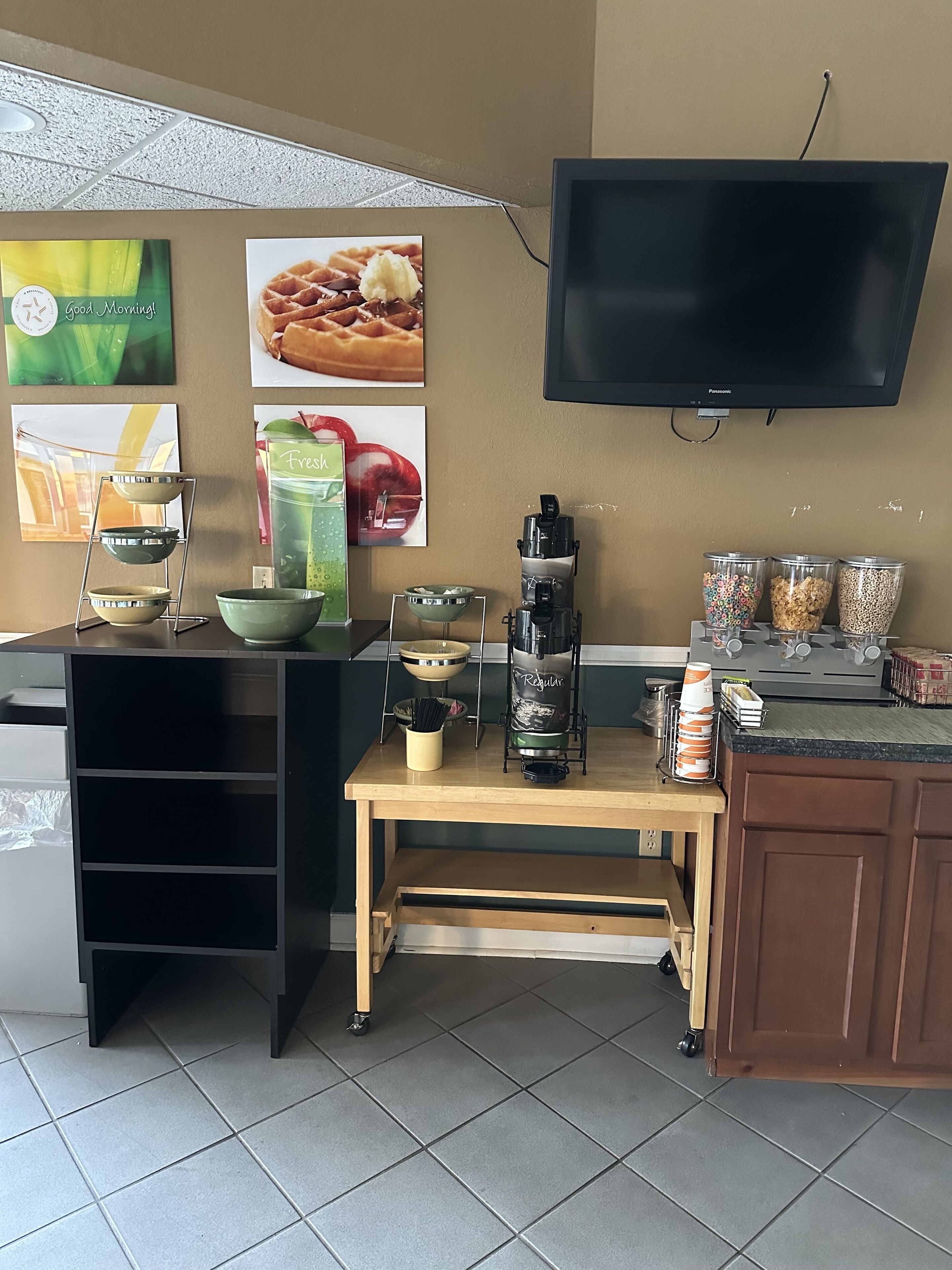 Una cocina equipada con cafetera, televisor montado en la pared y diversos utensilios y recipientes de cocina.