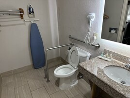 Un baño con inodoro blanco, lavamanos, secador de pelo y toallero.
