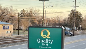A Quality Inn sign by Choice Hotels with a green background and a yellow logo.