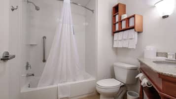 A modern bathroom with a bathtub, shower, toilet, and a vanity with a mirror.