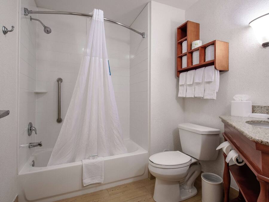 A modern bathroom with a bathtub, shower, toilet, and a vanity with a mirror.