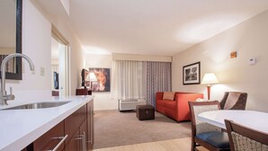 Ein modernes Hotelzimmer mit Küchenzeile, Essbereich und Wohnbereich.