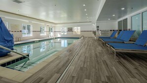Ein Poolbereich mit Holzboden, blauen Liegestühlen und einer gläsernen Barriere.