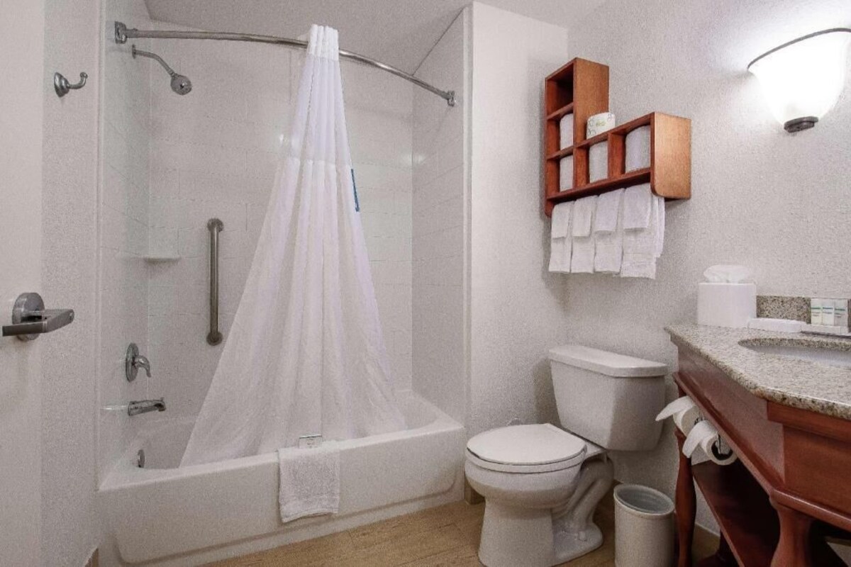 A bathroom with a bathtub, toilet, and a wooden shelf with towels.