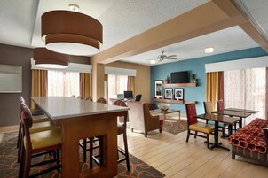 Habitación de hotel con comedor, televisor montado en la pared y ventilador de techo.