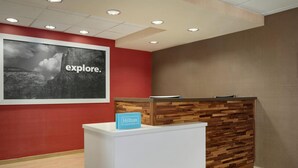 A reception desk with a wooden panel design, a 'Hilton Honors' sign, and a large 'explore.' poster on the wall.
