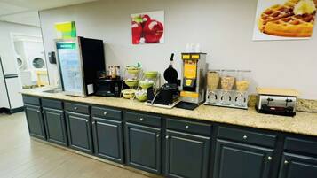 A kitchen area with a coffee machine, waffle maker, and various food containers.