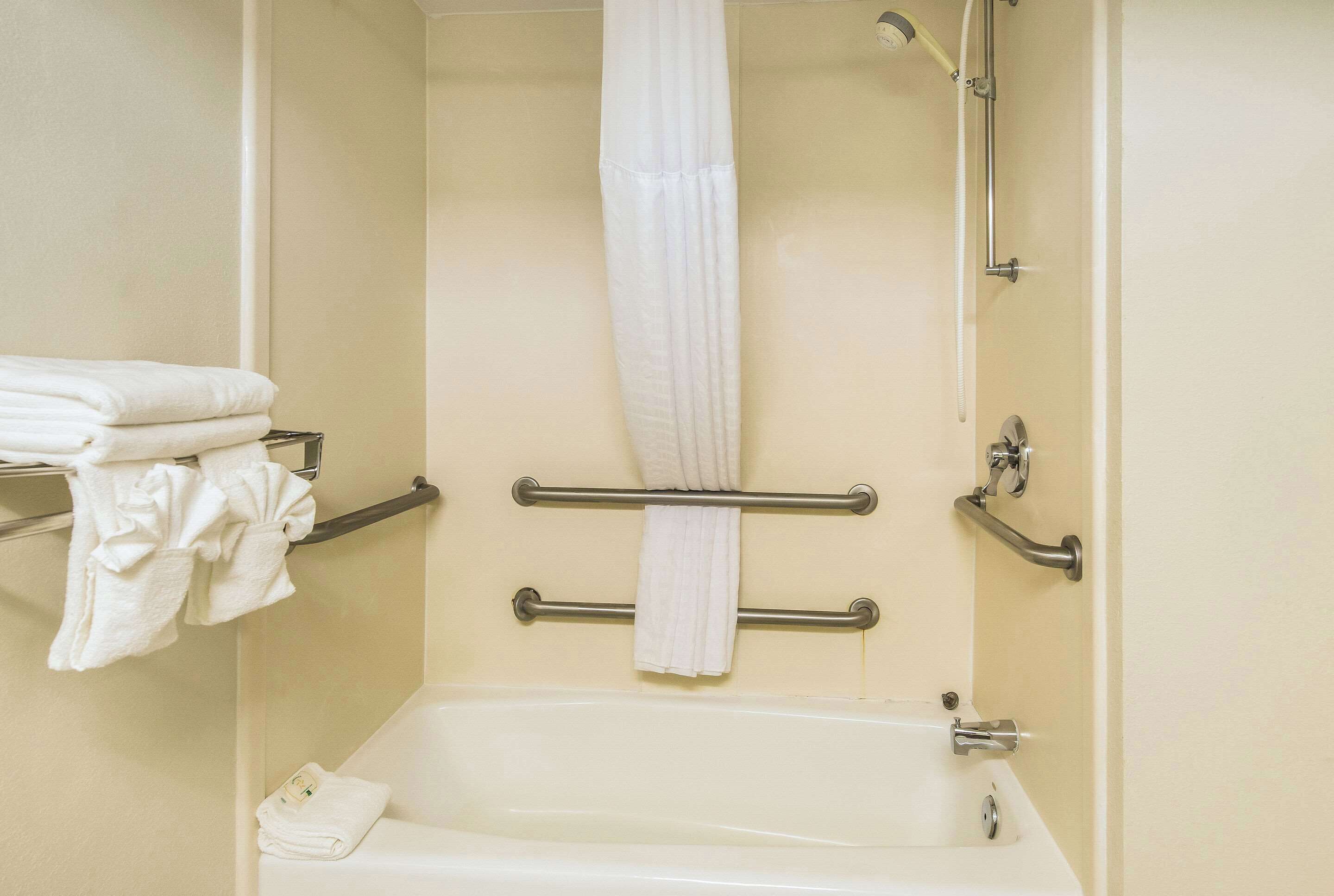 A bathroom with a bathtub, a shower, and a towel rack with folded towels.