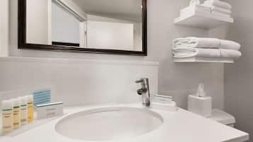 A bathroom with a white sink, a mirror, and a towel rack.