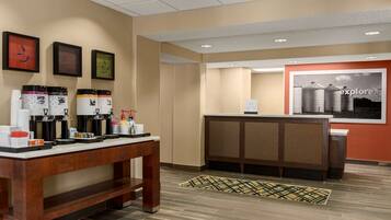 A reception area with a coffee station, a reception desk, and a wall with framed artwork.