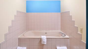 A bathroom with a bathtub, two towels, and a blue wall.