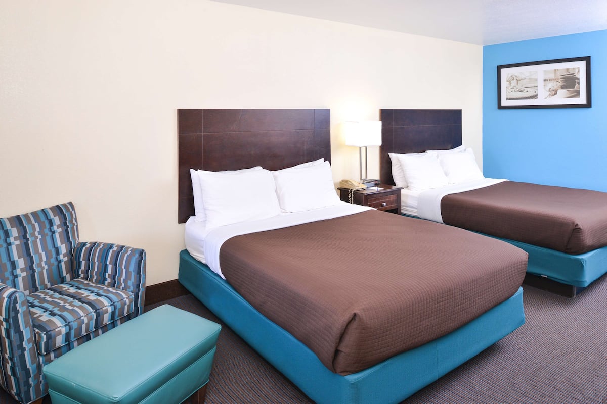 A hotel room with two beds, a sofa, and a nightstand.