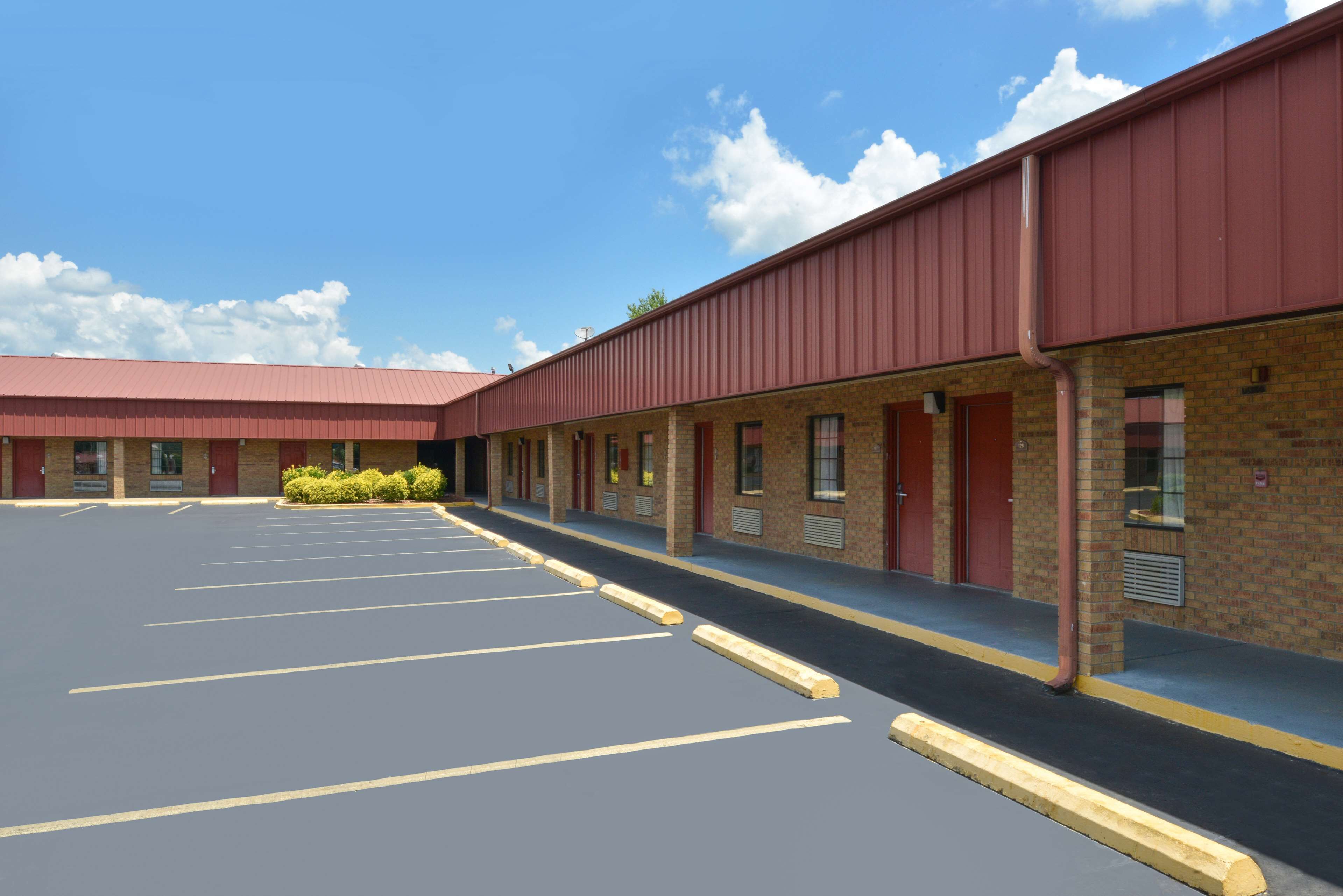 A motel with a parking lot, multiple rooms, and a brick facade.