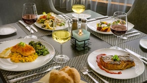 A dining table set with plates of food, glasses of wine, and a candle.