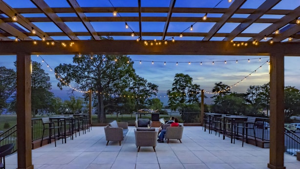 An outdoor patio with string lights, seating, and a view of the park.