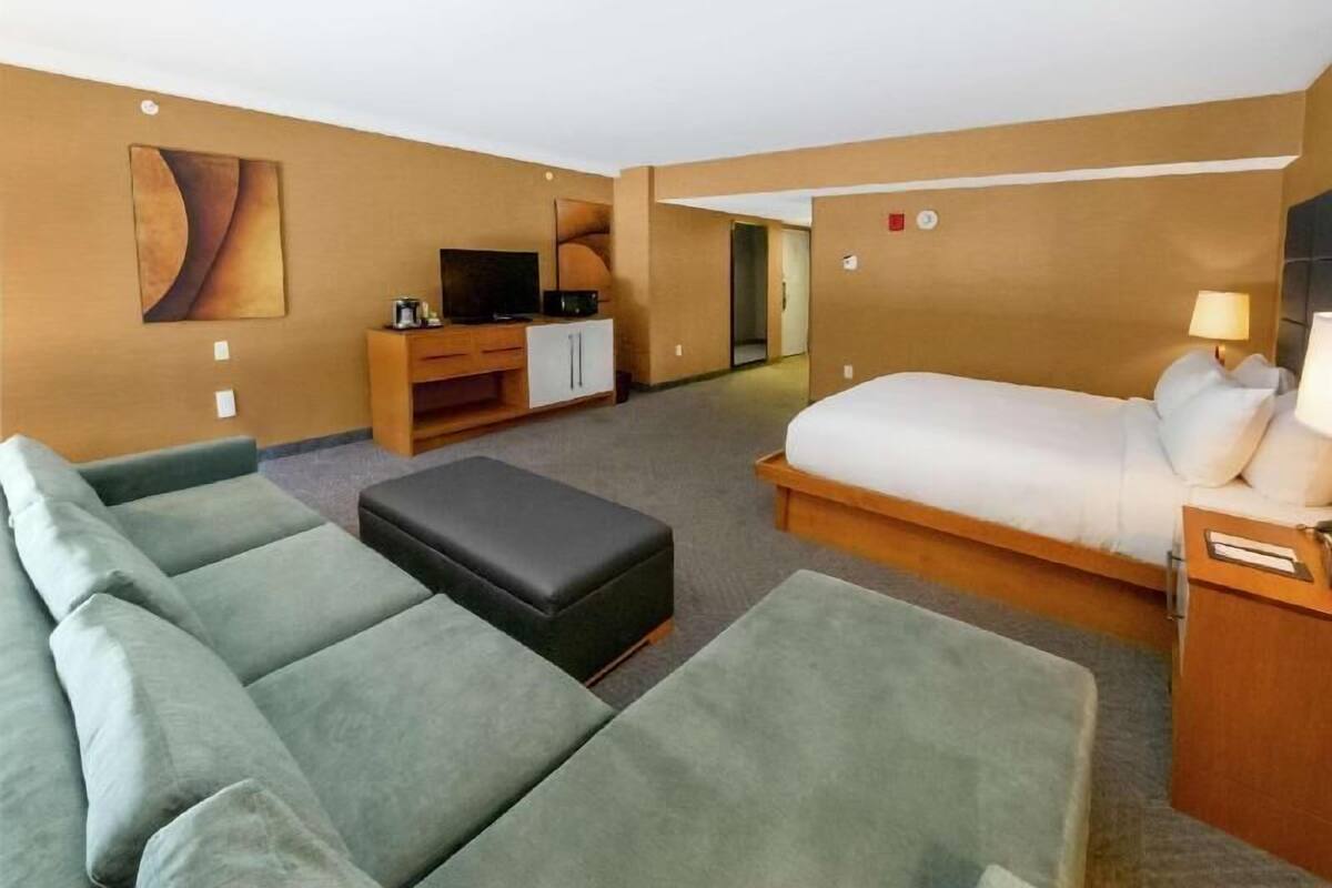 Een hotelkamer met een bank, een bed, een televisie en een bureau.