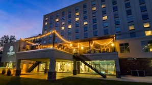A hotel with a modern design, featuring a prominent entrance with a staircase and a covered area adorned with string lights.