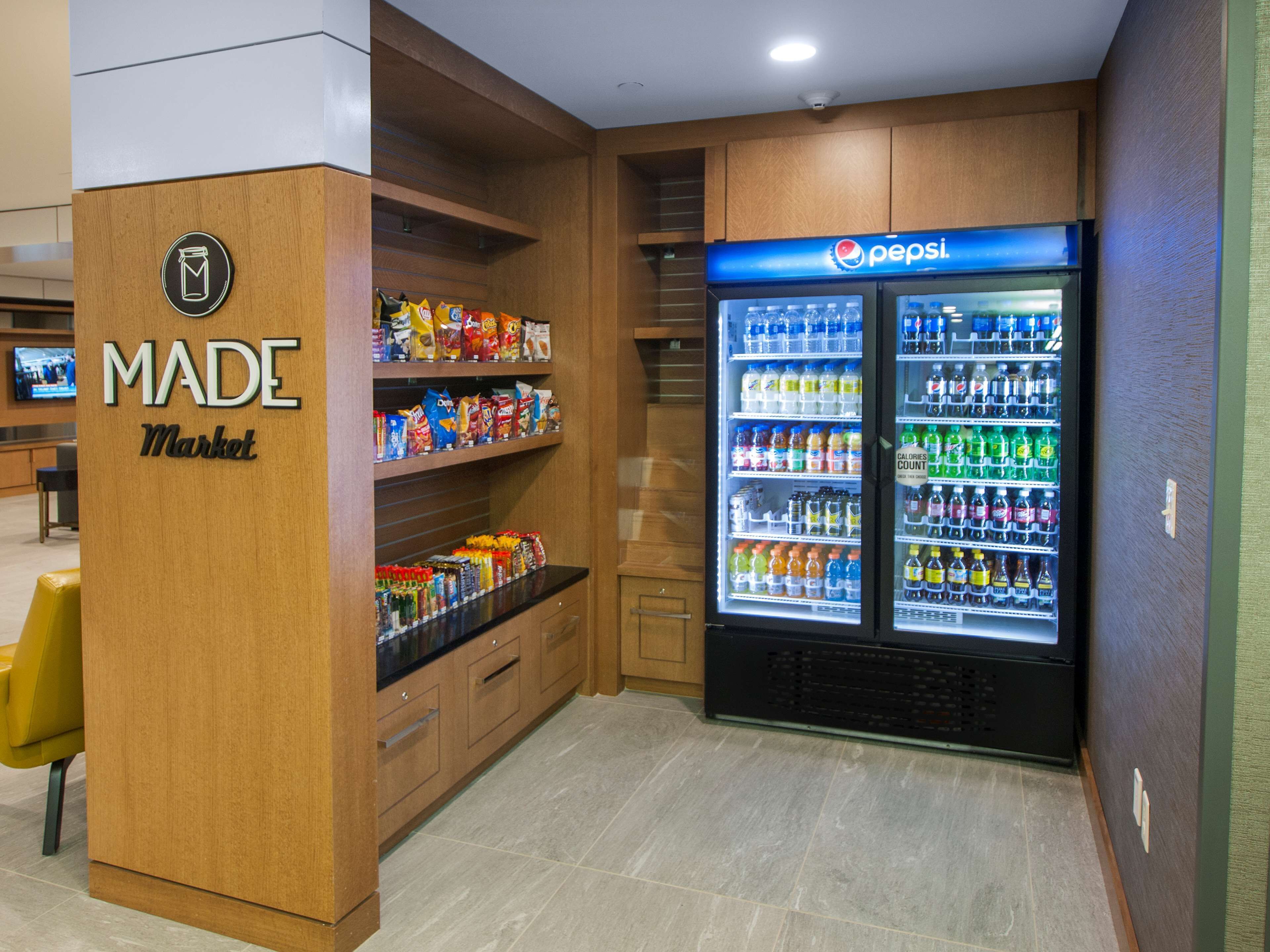 Zona de máquinas expendedoras con un letrero 'MADE Market' y un refrigerador de Pepsi.