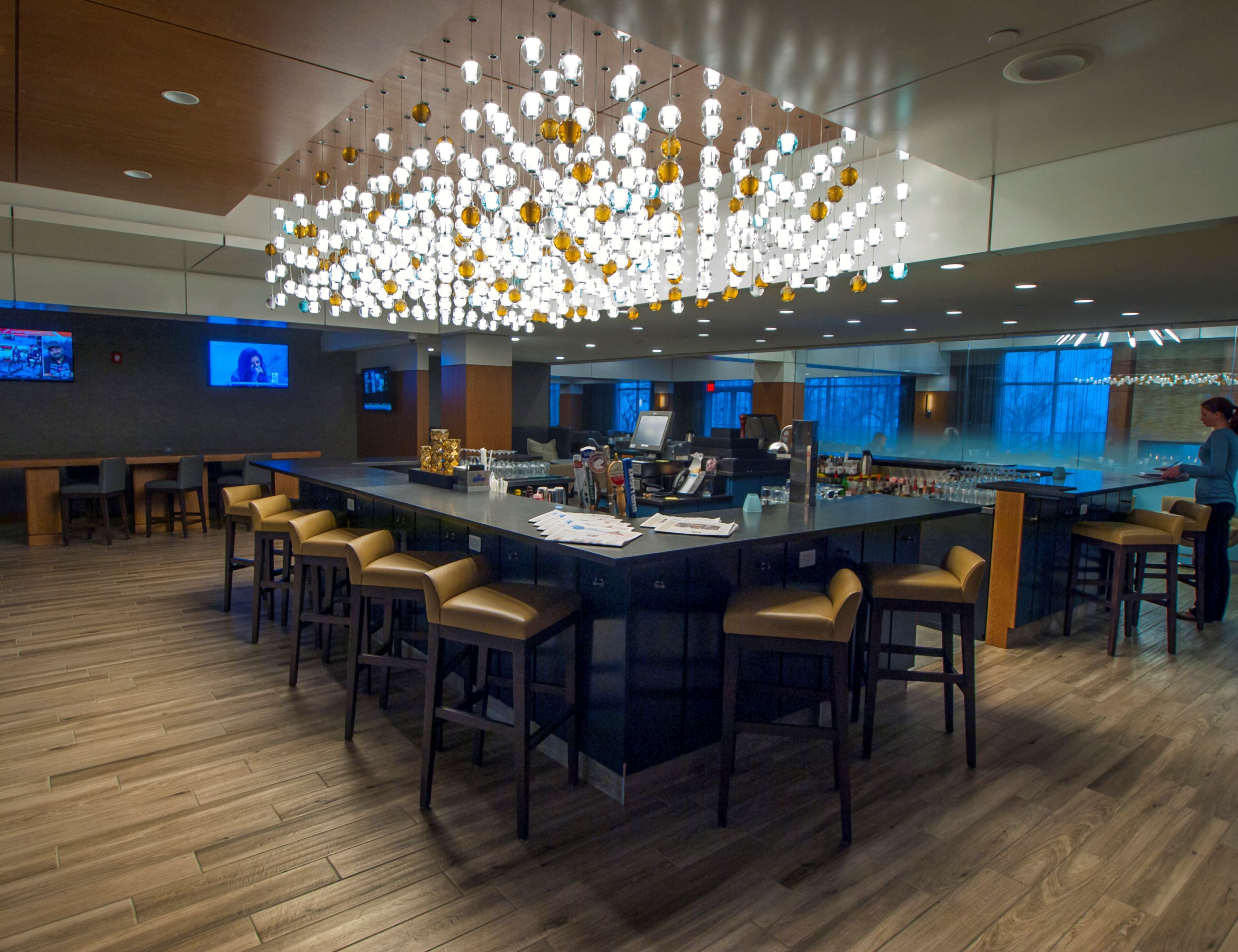 A modern bar area with a central island, bar stools, and a unique chandelier.
