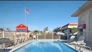 A swimming pool with lounge chairs and a sign for Ramada. - Days Inn by Wyndham San Marcos (San Marcos)
