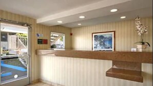 A reception area with a counter, framed artwork, and a potted orchid. - Days Inn by Wyndham San Marcos (San Marcos)