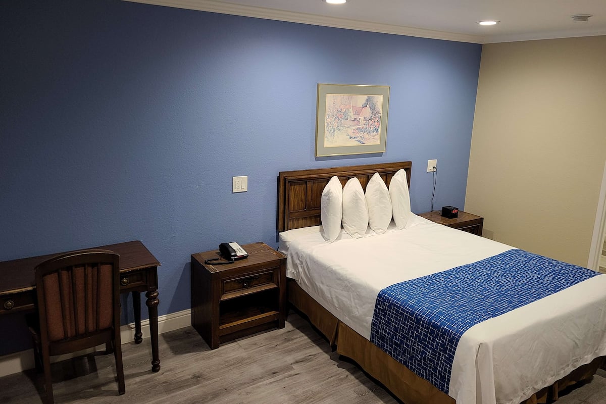 Une chambre d’hôtel avec un lit, un bureau et une chaise.