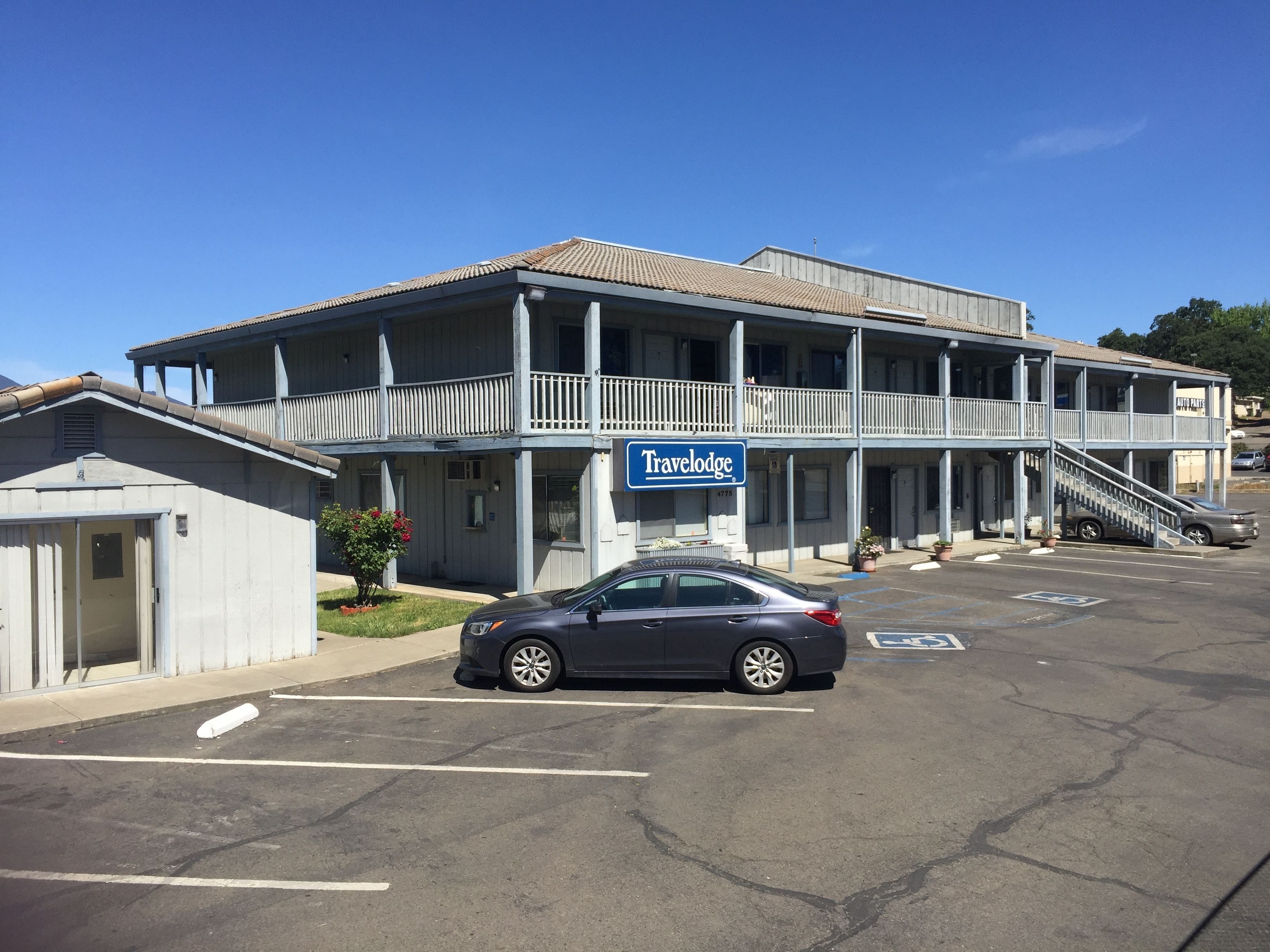 Ein Travelodge Hotel mit zweistöckiger Bauweise, einem Balkon und einem Parkplatz mit einem Auto.