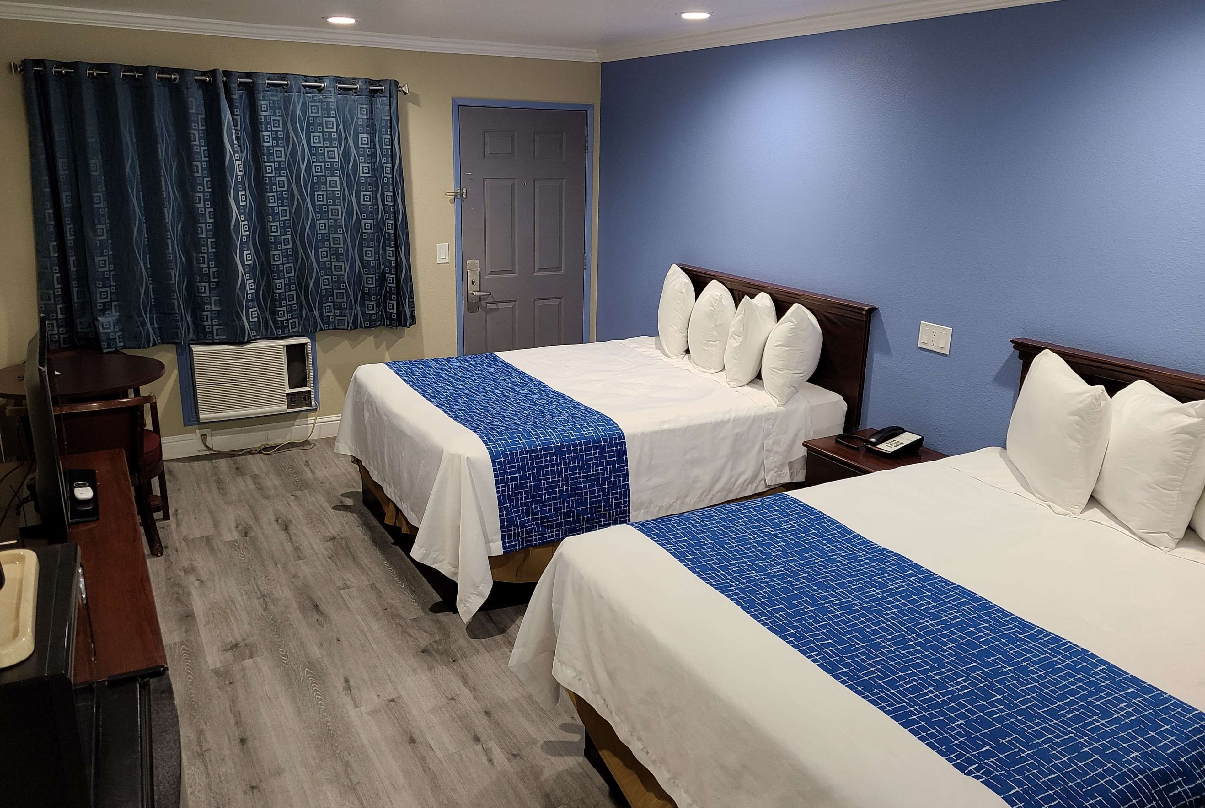 A hotel room with two beds, a desk, and a chair.