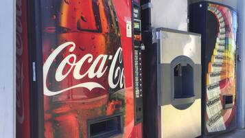 Three vending machines, one with a Coca-Cola logo, one with a vitamin water logo, and one with a generic label.