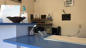 Un mostrador de recepción de hotel con una encimera azul, un reloj digital, un letrero de Wyndham Rewards y una planta pequeña.