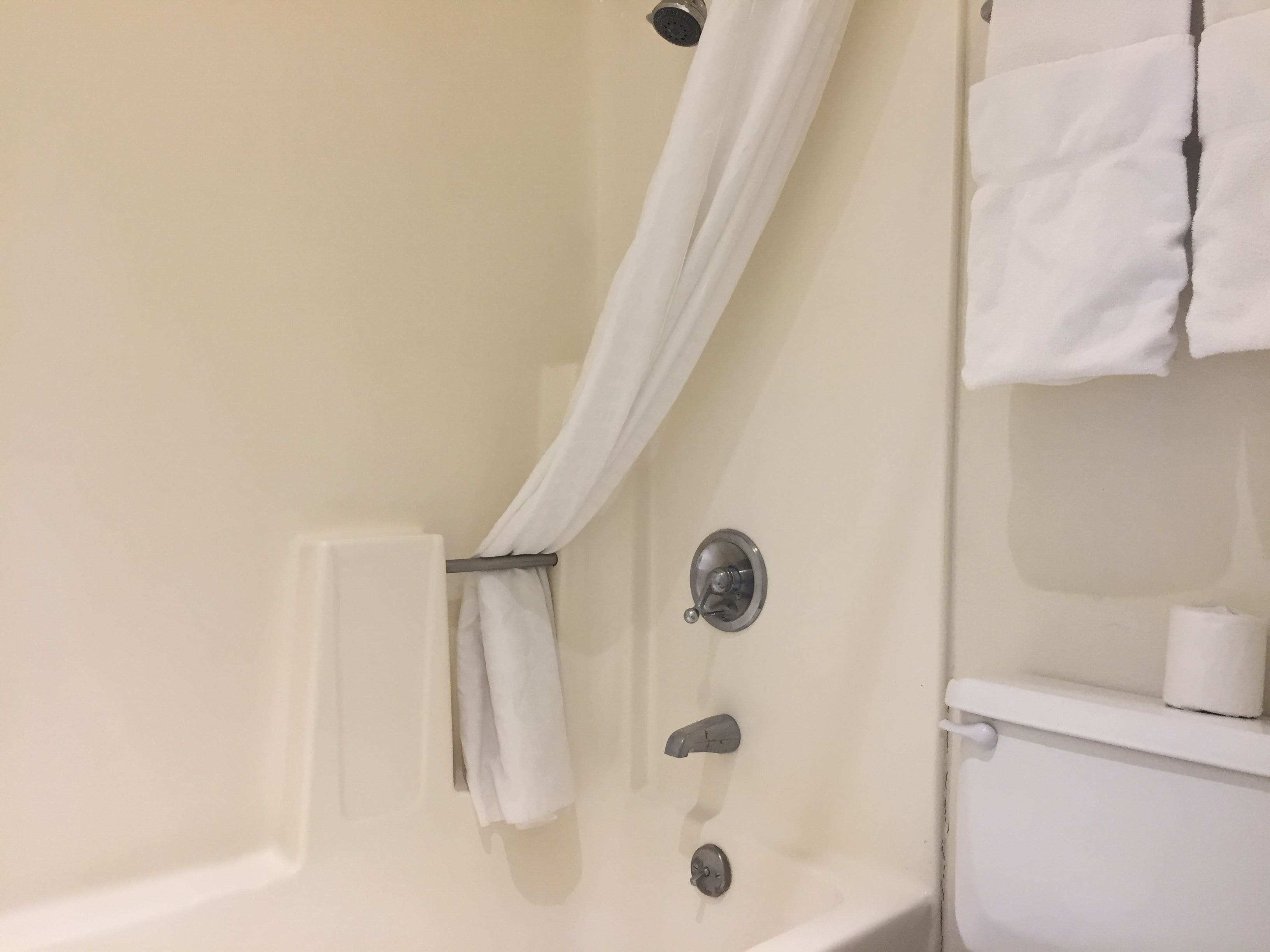A bathroom with a bathtub, a shower curtain, a towel rack, and a toilet.
