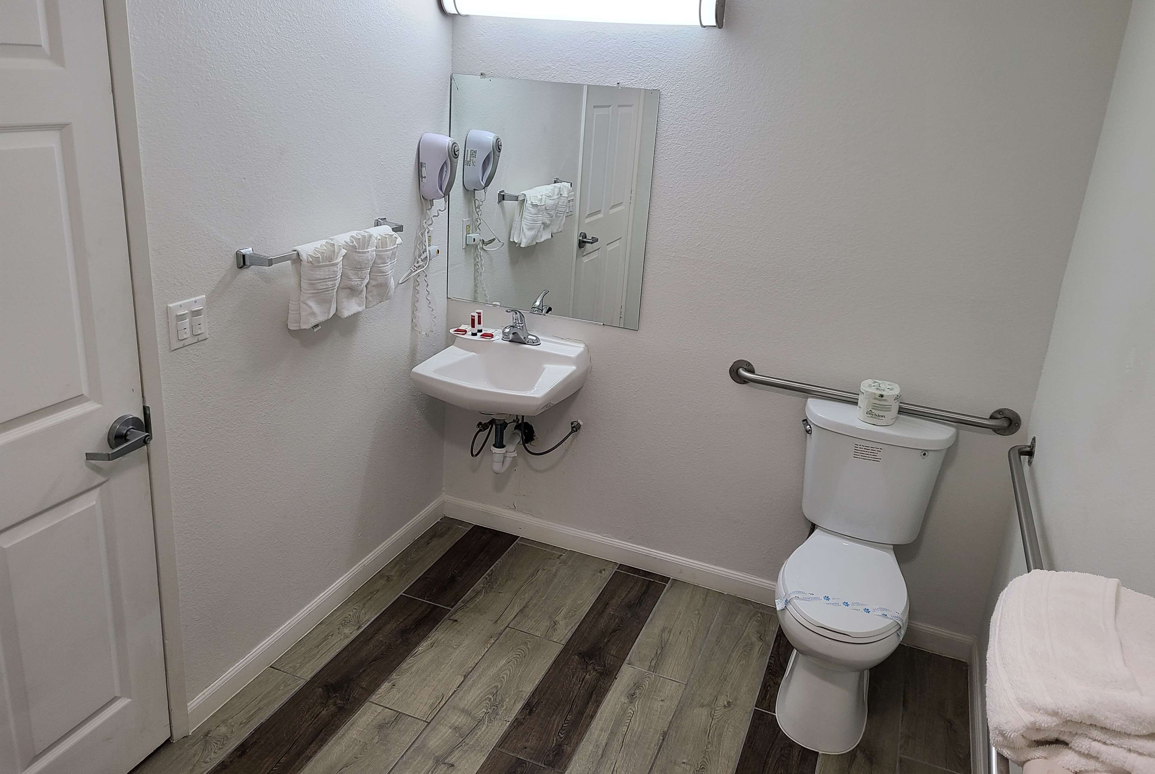 A bathroom with a white sink, a toilet, a mirror, and a towel rack.