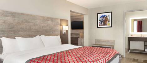 A hotel room with a large bed, a TV, a painting, and a bathroom.