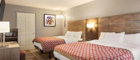 Une chambre d’hôtel avec deux lits, un bureau, une télévision et un tableau encadré au mur.
