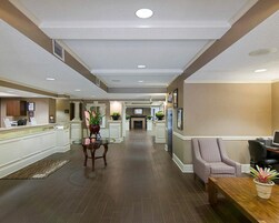 Un hall de hotel con mostrador de recepción, zona de estar y chimenea.