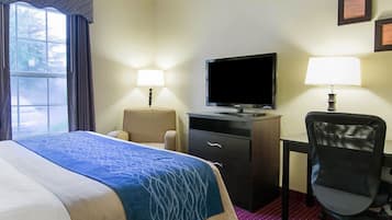 Une chambre d’hôtel comprenant un lit, un bureau, une chaise, un téléviseur et deux lampes.