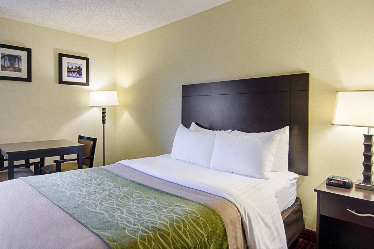 A hotel room with a bed, a desk, and two lamps.