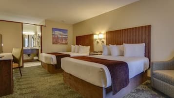 A hotel room with two beds, a desk, a chair, and a bathroom visible through an open door.