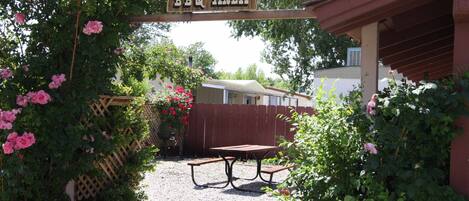 A wooden sign reading "Vagabond BBQ Area" above a gravel path leading to a picnic table.