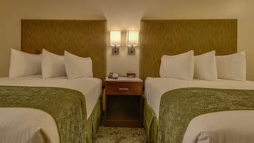 A hotel room with two single beds, a nightstand with a lamp, and a patterned carpet.