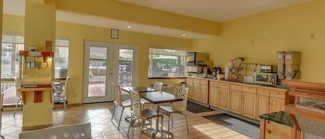 Una cocina con comedor, que incluye una mesa, sillas, un microondas y un refrigerador.