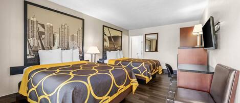 Habitación de hotel con dos camas, un escritorio, una silla y un televisor.