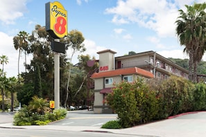 A motel with a Super 8 sign, a building with a red roof, and lush greenery around.