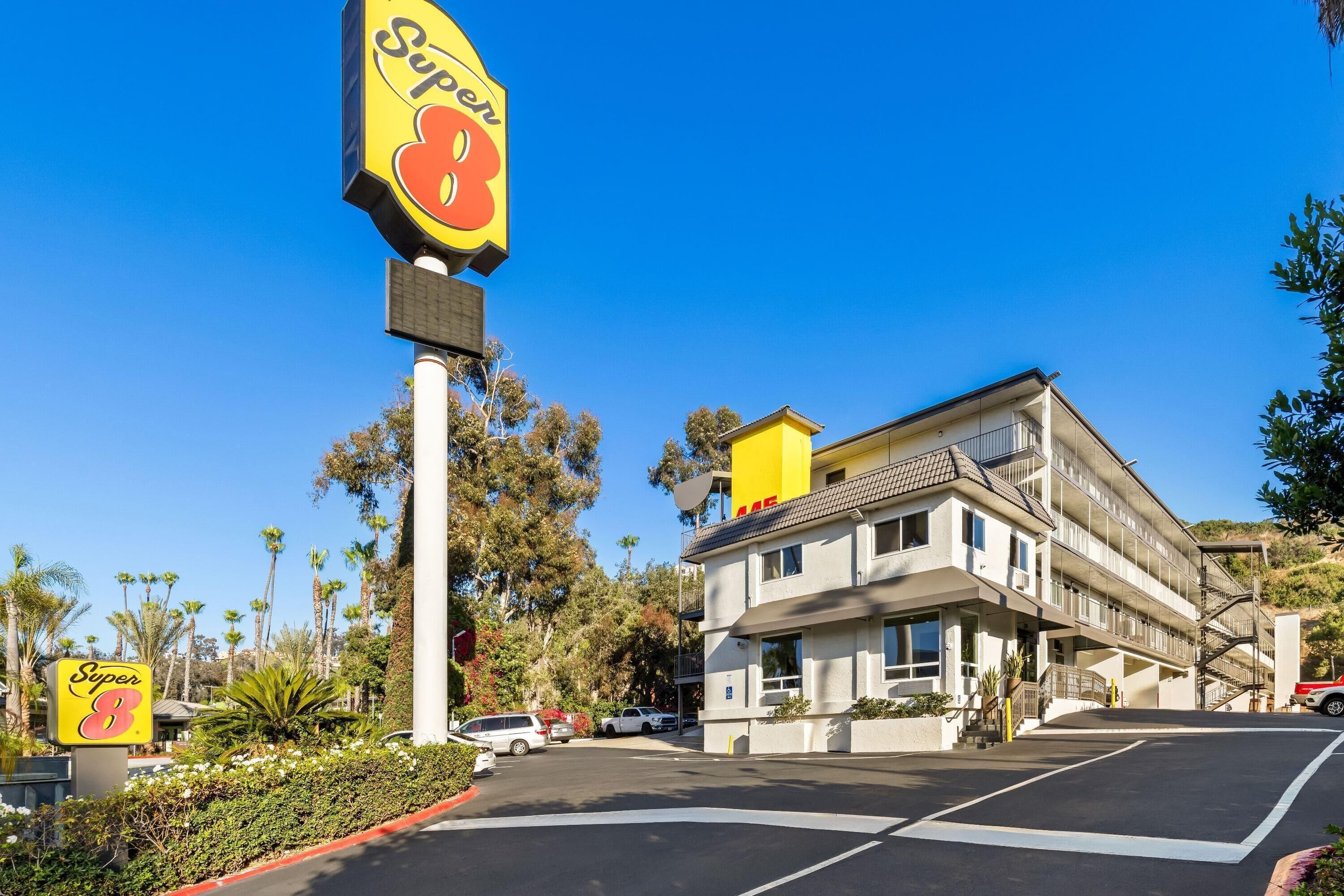 A hotel with a prominent 'Super 8' sign, a parking lot, and a multi-story building with balconies.