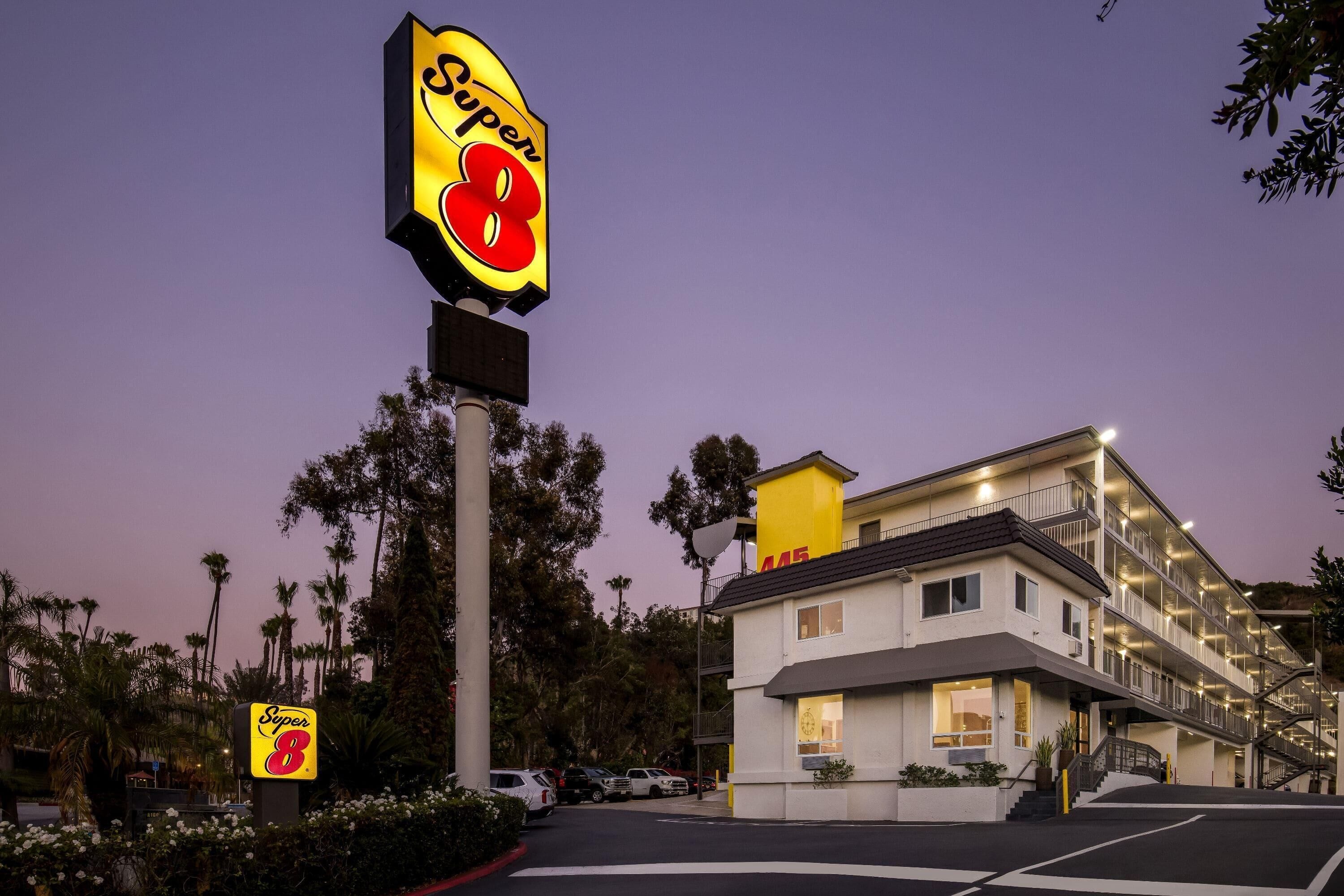 A Super 8 motel with a prominent sign, a parking lot, and a multi-story building with balconies.