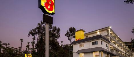 A Super 8 motel with a prominent sign, a parking lot, and a multi-story building with balconies.