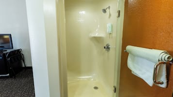 A shower with a glass door, a towel rack with a towel, and a small shelf with toiletries.